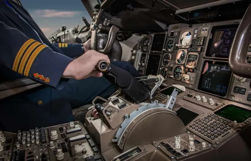 Pilot adjusting thrust lever in cockpit of commercial aircraft during flight